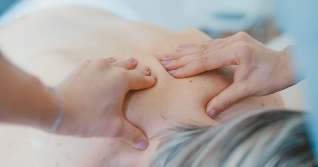 person massaging the back of a woman