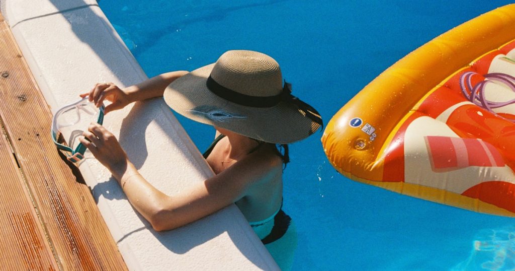 A man sitting on the side of a swimming pool next to an inflatable