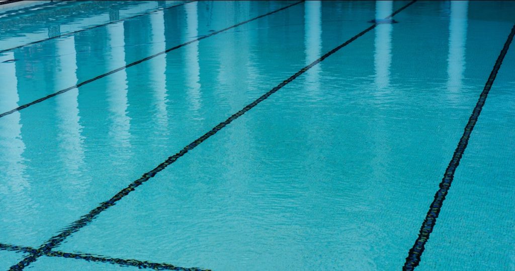 A swimming pool with a tiled floor and blue water