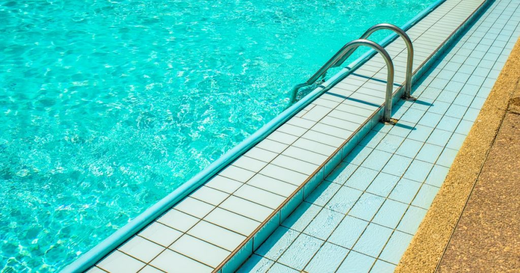 a swimming pool with a long metal railing next to it