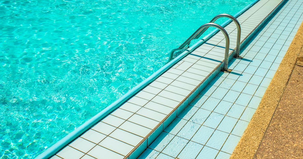 a swimming pool with a long metal railing next to it