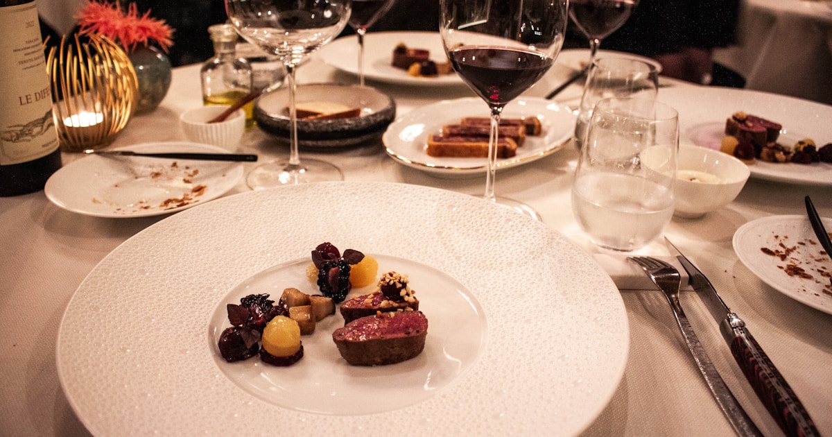 A table is set with wine glasses and plates of food