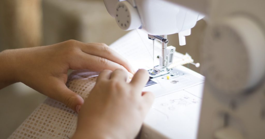 a close up of a person using a sewing machine