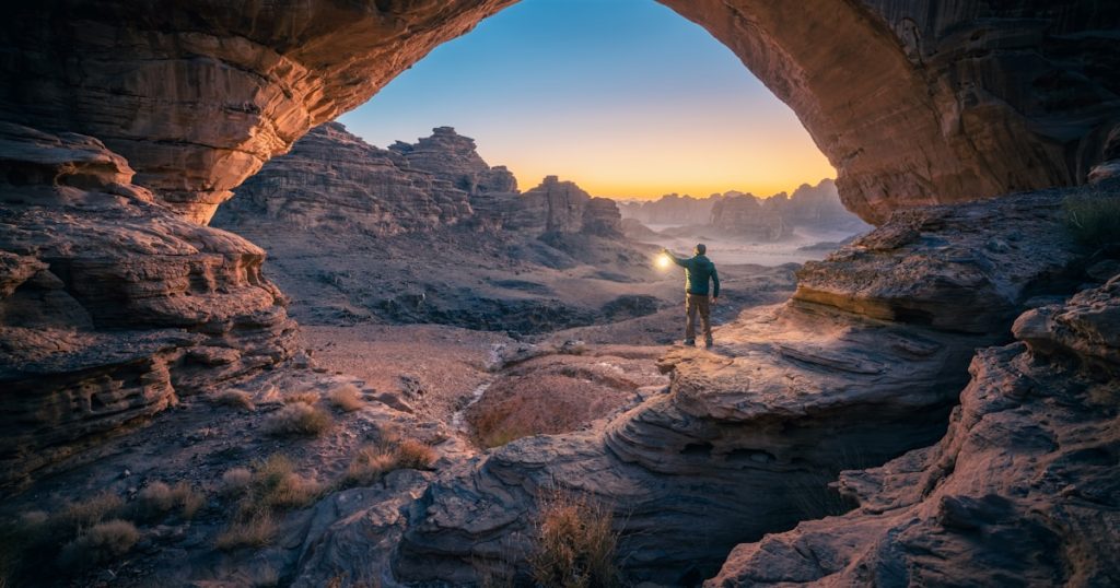 a man standing in a cave at sunset